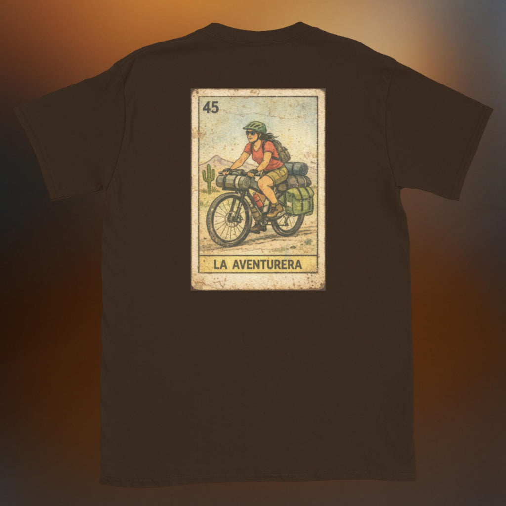 Latino apparel graphic tee featuring a vintage Mexican Loteria card design labeled "LA AVENTURERA" with a cyclist riding a bike, perfect for summer streetwear and cycling enthusiasts.