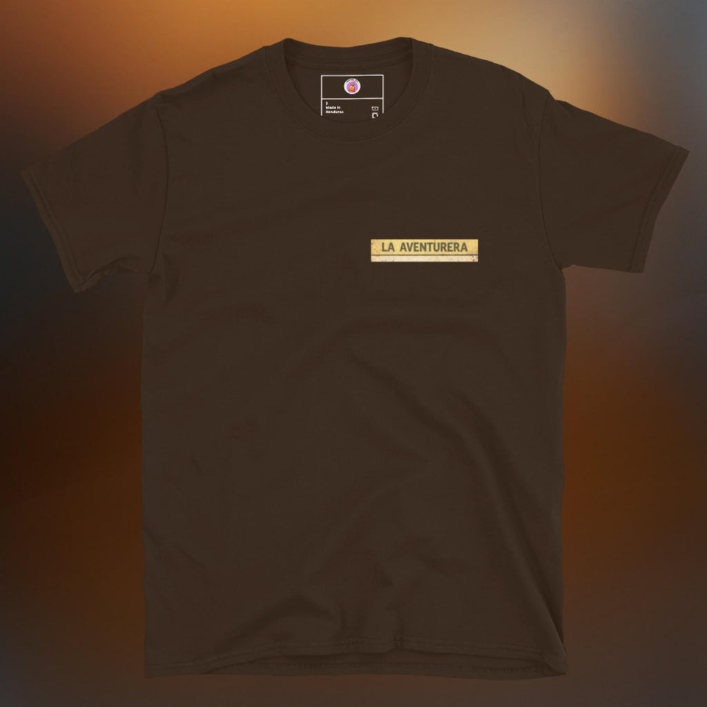 Latino apparel graphic tee featuring a vintage Mexican Loteria card design labeled "LA AVENTURERA" with a cyclist riding a bike, perfect for summer streetwear and cycling enthusiasts.