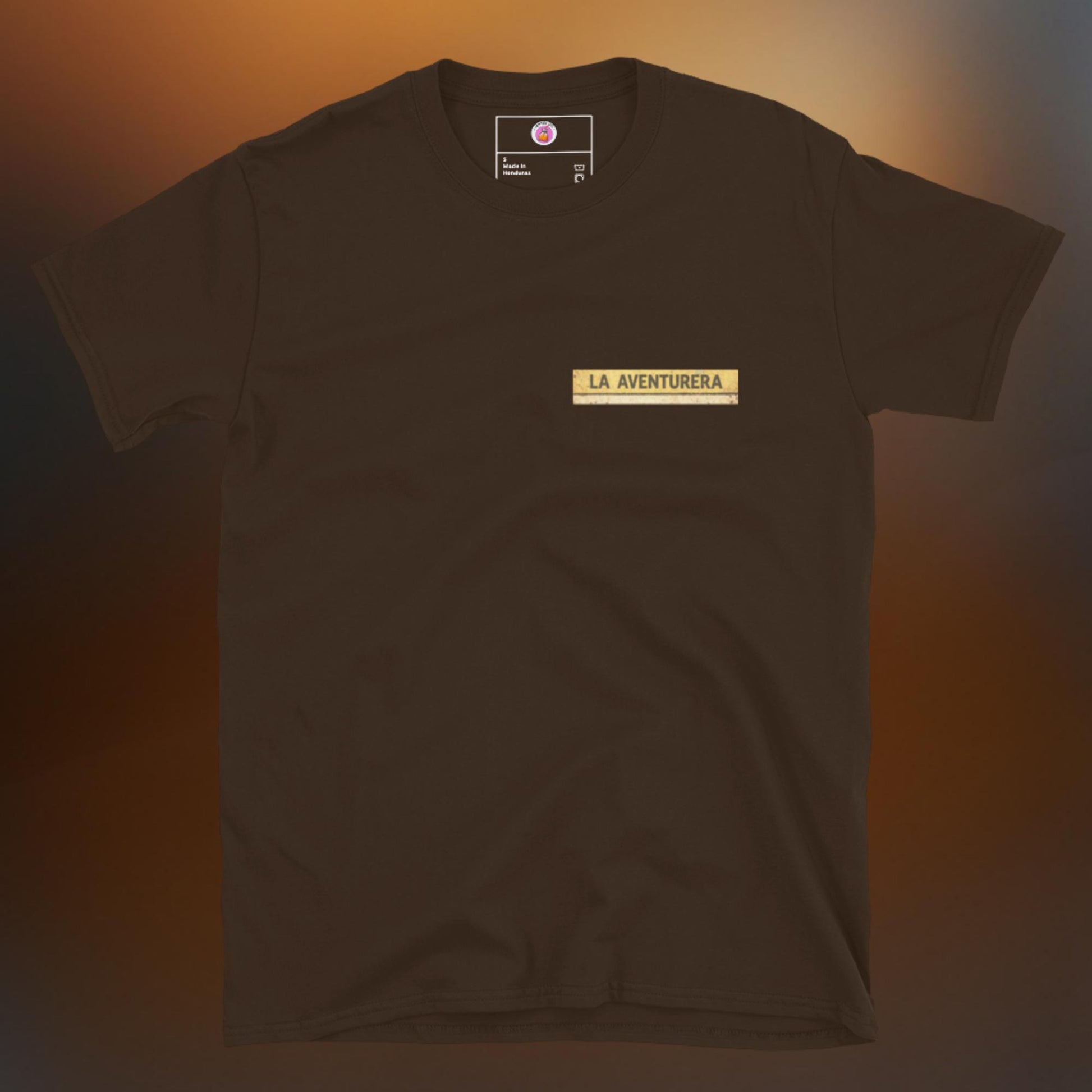 Latino apparel graphic tee featuring a vintage Mexican Loteria card design labeled "LA AVENTURERA" with a cyclist riding a bike, perfect for summer streetwear and cycling enthusiasts.