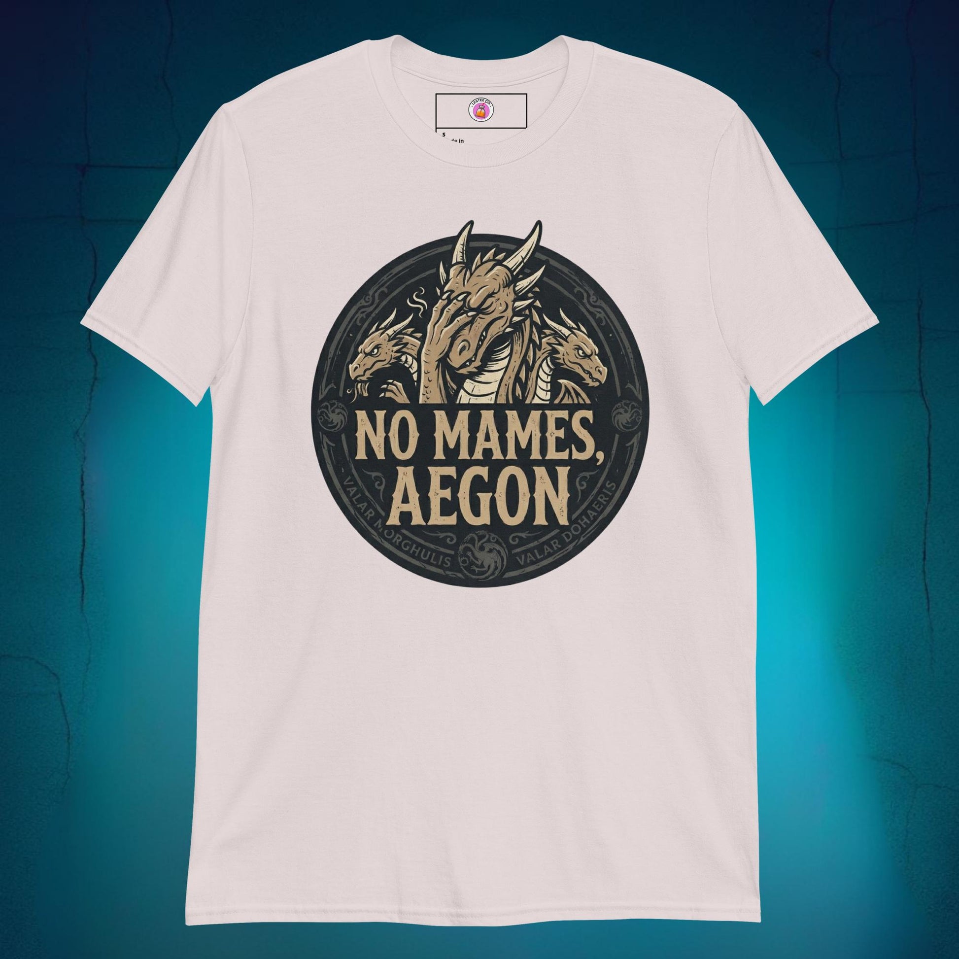 A close-up mockup of a unisex t-shirt featuring a graphic design of a dragon with a disappointed facial expression and the funny Spanish phrase text "no mames Aegon" written underneath.